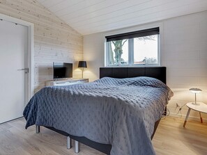 A bedroom with a bed, a TV, a lamp, and a window. - 5 Star Holiday Home in Hejls (Hejls)