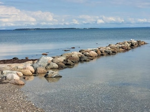 A rocky shoreline with a calm sea and distant land.