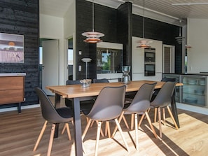 A modern dining area with a wooden table, grey chairs, and pendant lighting. - 5 Star Holiday Home in Hejls (Hejls)