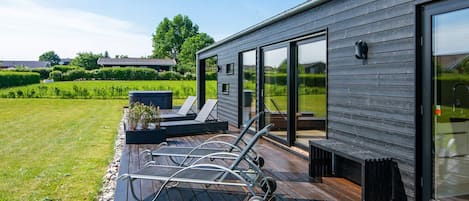 A modern house with a deck, outdoor seating, and a large glass door.
