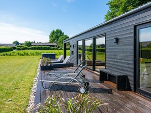 A modern house with a deck, outdoor seating, and a large glass door.