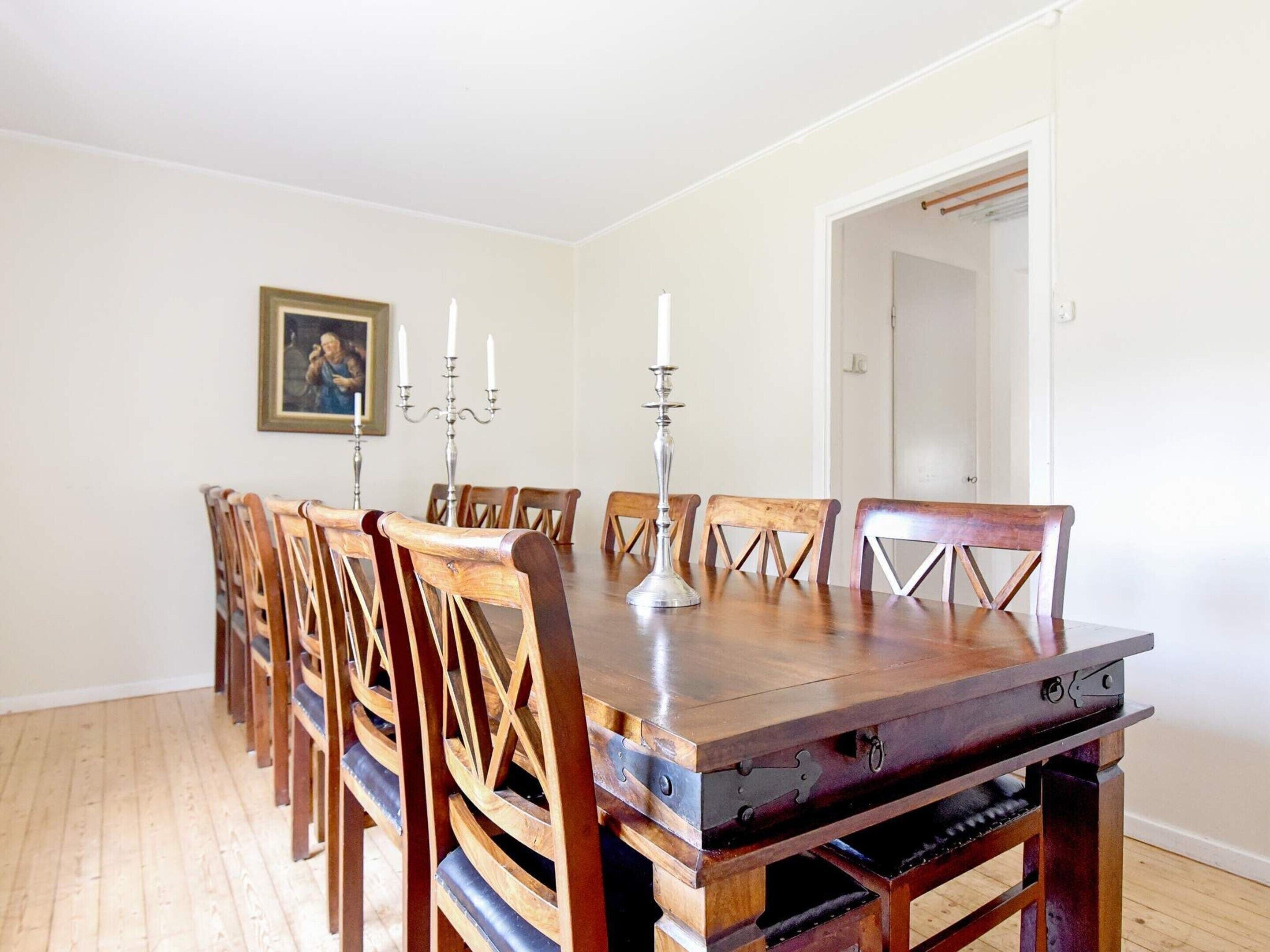 A dining room with a wooden table and chairs, a candelabra, and a framed picture on the wall.