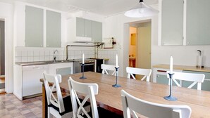 Une cuisine moderne avec des meubles blancs, une table à manger en bois et des chaises blanches.
