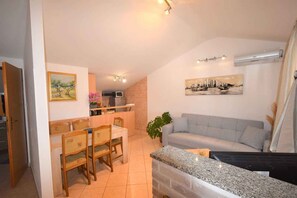 A compact living space with a dining area, a sofa, a TV, and a kitchen area.
