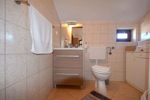 A bathroom with a toilet, a sink, a mirror, and a towel hanging on the wall. - Holiday apartment in attic with sea view (Njivice)