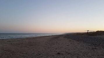 Een strand met een bord, kiezels en de oceaan.