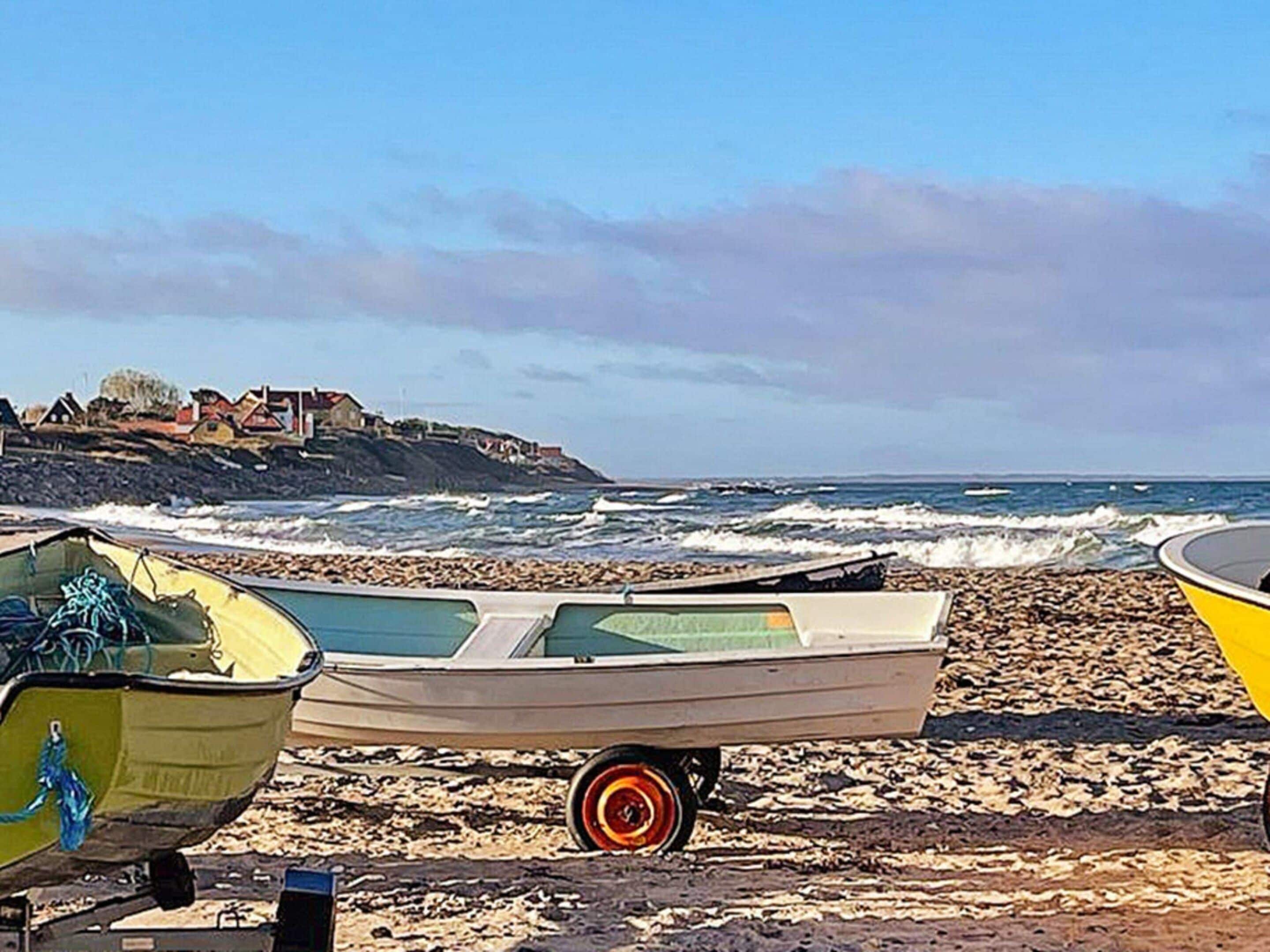 A beach with boats and a rocky shoreline.