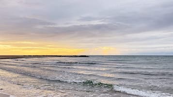 Een strand met golven en een bewolkte lucht.