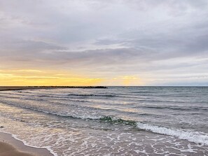 A beach with waves and a cloudy sky.