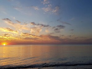 Um pôr do sol sobre um mar calmo, com o horizonte nítido.