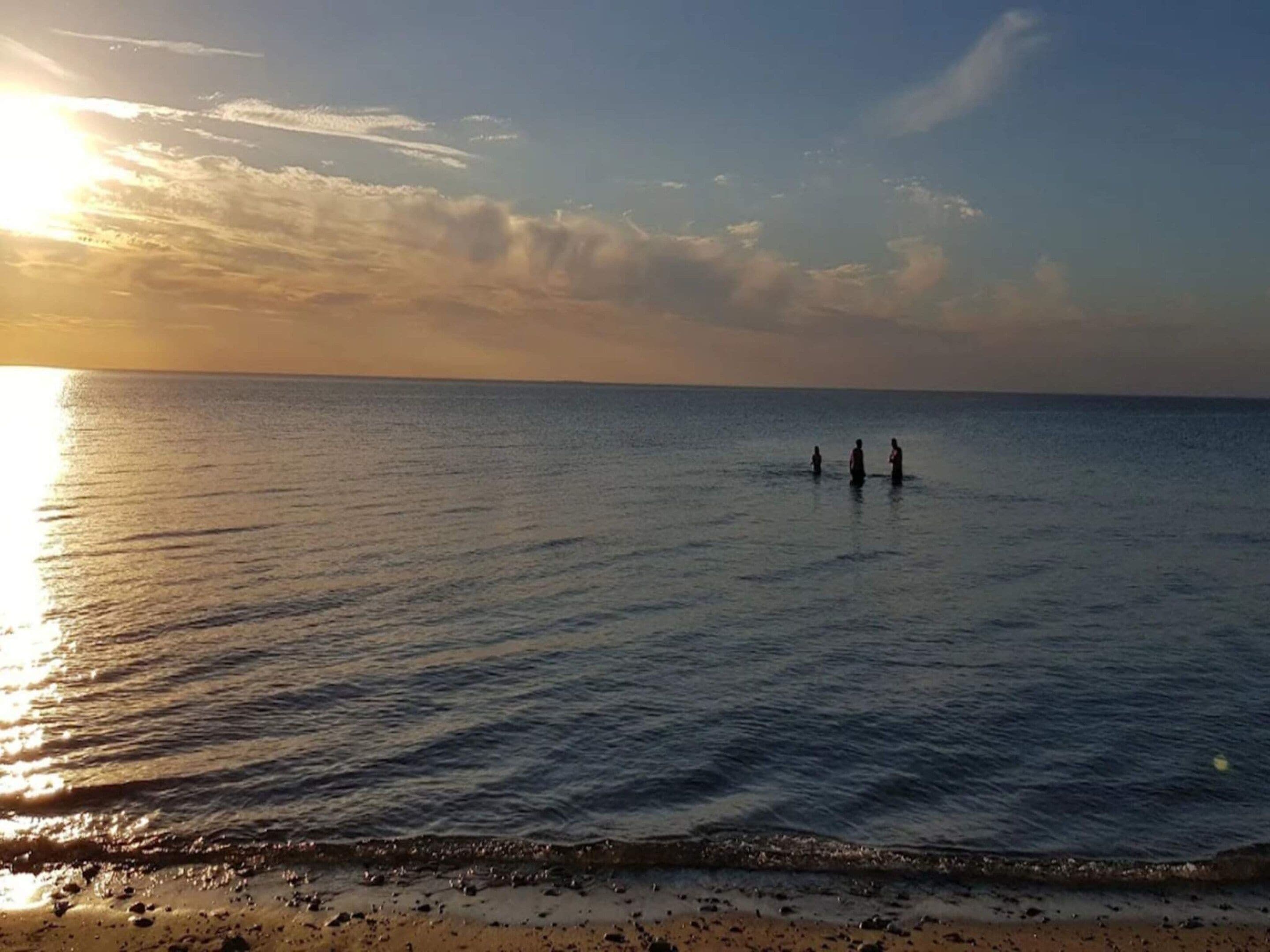 A beach scene with calm water and a sunset.