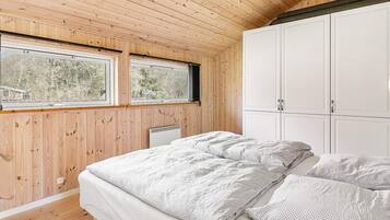 A bedroom with a bed, two windows, a radiator, and a wardrobe.