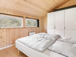 A bedroom with a bed, two windows, a radiator, and a wardrobe. - 4 Star Holiday Home in Frederiksvaerk (Frederiksvaerk)