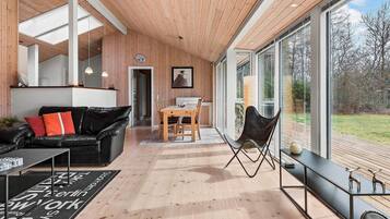 Een modern interieur met een houten plafond, een eethoek en grote ramen met uitzicht op het landschap.
