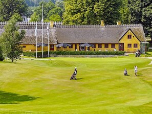 A golf course with a yellow building in the background. - 4 Star Holiday Home in Frederiksvaerk (Frederiksvaerk)