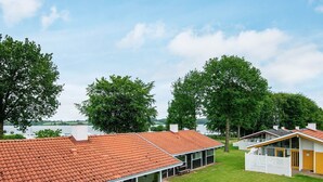 A row of modern cabins with red-tiled roofs, large windows, and a grassy lawn in front.