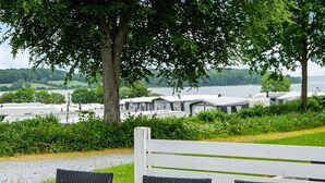 A view of a lakeside area with a row of mobile homes and a wooden fence in the foreground.