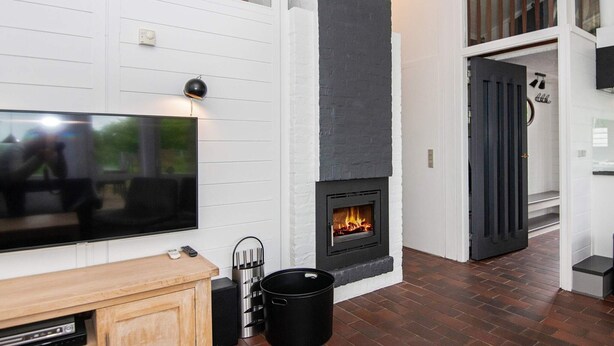 A modern living room with a fireplace, a flat-screen TV, and a wooden entertainment unit.