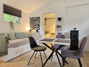 A cozy living room with a sofa, a dining table with chairs, a fireplace, and a wall decorated with framed photos. - 4 Star Holiday Home in Loddekopinge (Loddekopinge)