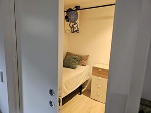 A bedroom with a bed, a nightstand, a dresser, and a wall-mounted shelf with a decorative item. - 4 Star Holiday Home in Loddekopinge (Loddekopinge)