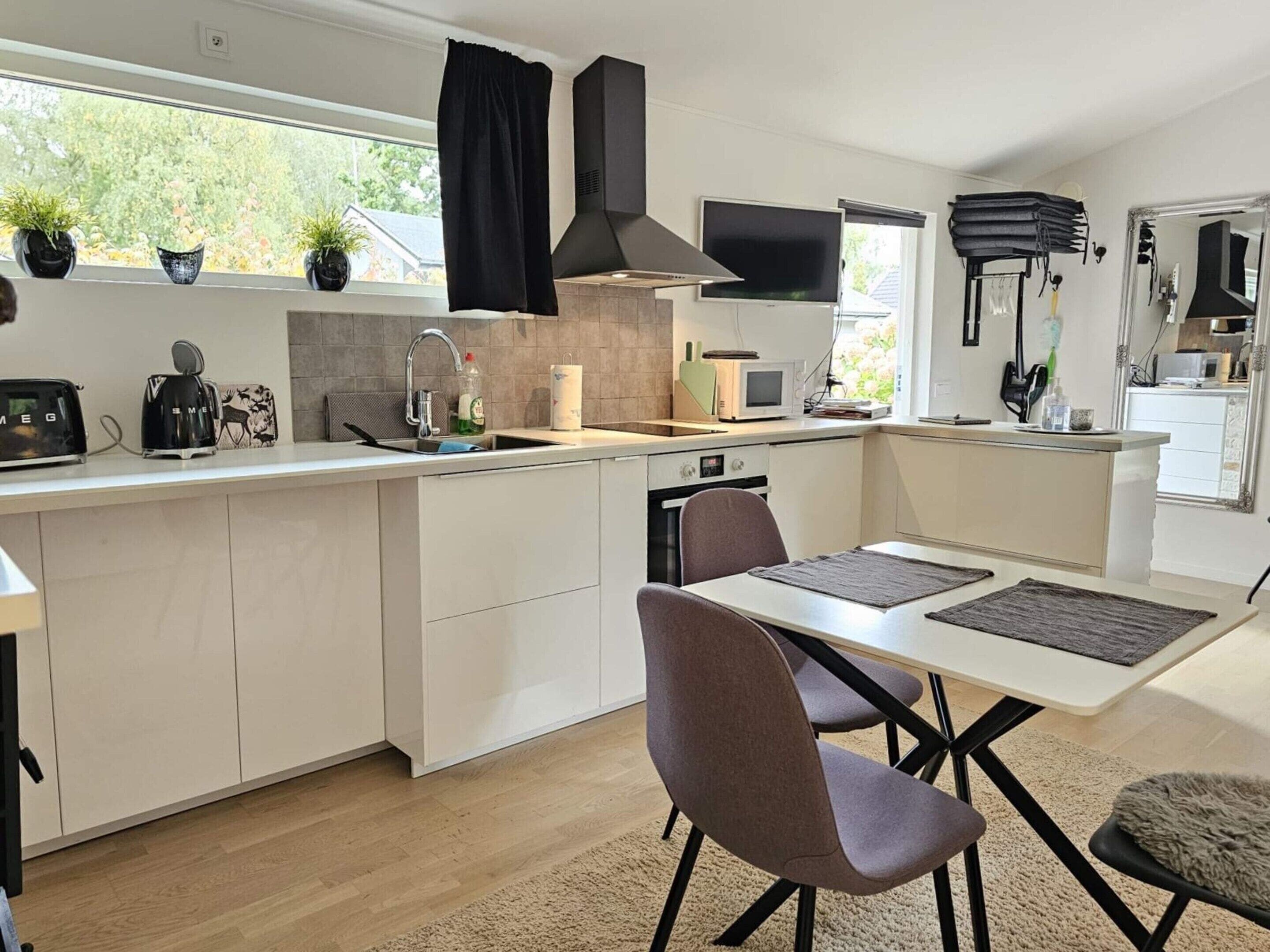 A modern kitchen with white cabinetry, a built-in microwave, a gas stove, and a dining area with a table and chairs.
