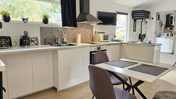 A modern kitchen with white cabinetry, a built-in microwave, a gas stove, and a dining area with a table and chairs.