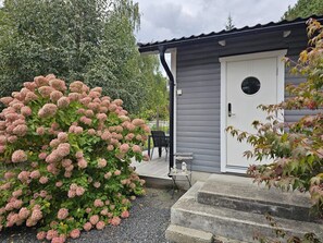 A house with a grey exterior, a white door with a round window, and a small outdoor seating area with a table and chairs. - 4 Star Holiday Home in Loddekopinge (Loddekopinge)