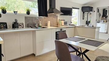 Una cocina moderna con una isla central, electrodomésticos integrados y un comedor con mesa y sillas.