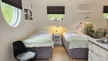 A bedroom with two beds, a desk, a chair, and a window with blinds.