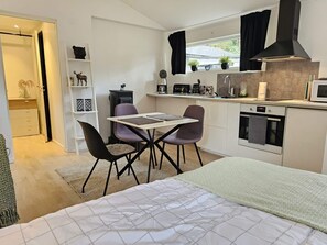 Una cocina compacta con comedor, una cama y un pequeño espacio de estar.