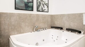 Un baño moderno con una bañera independiente, un lavamanos empotrado y dos láminas botánicas enmarcadas.