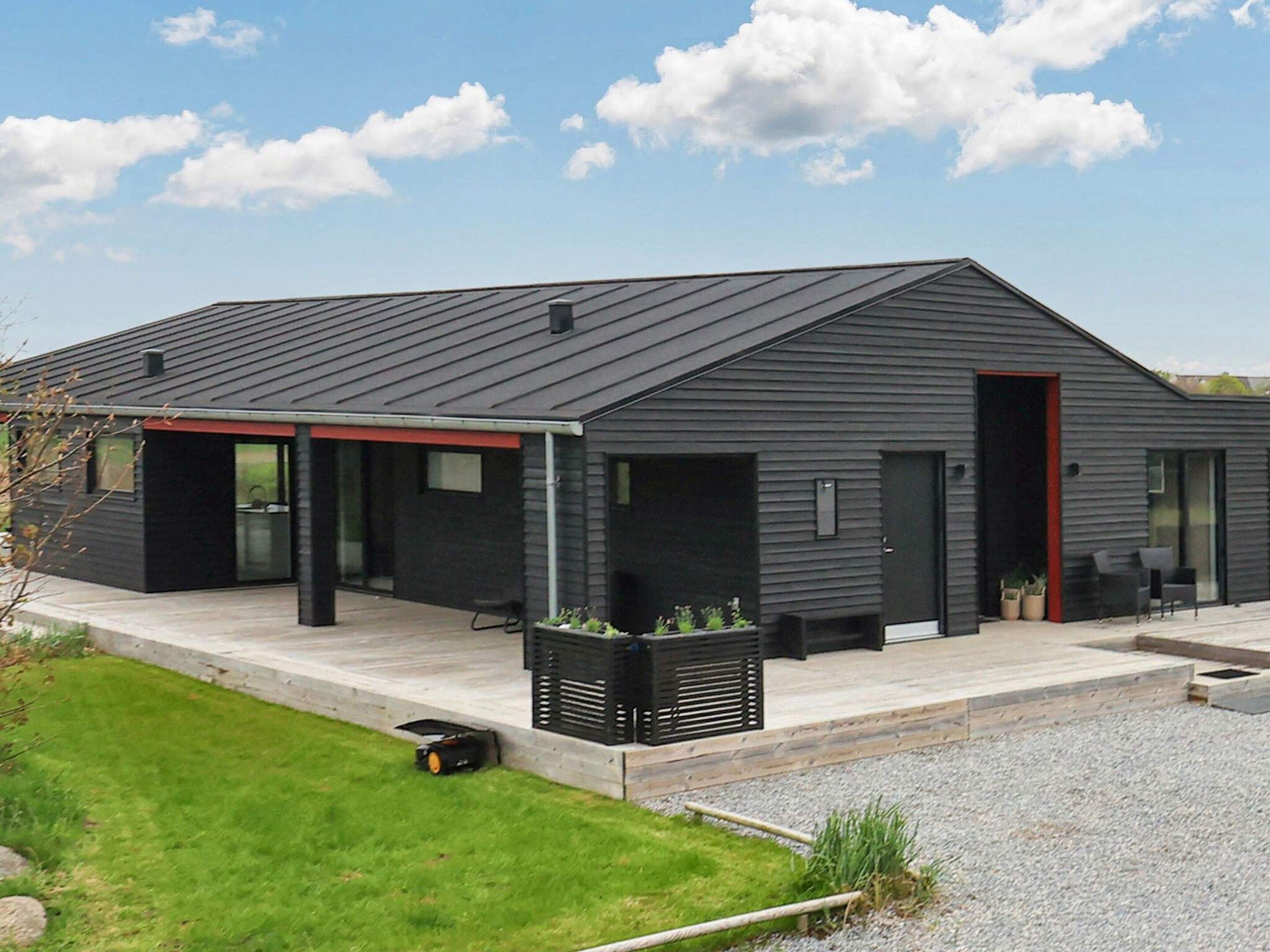 A modern building with a flat roof, a covered porch area, and a door leading to the interior.