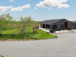 A modern black building with a covered porch and a gravel driveway.