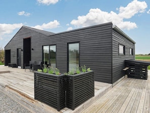 Ein modernes Gebäude mit flachem Dach, großen Fenstern und einer Holzterrasse.