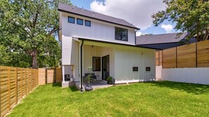 Une maison moderne à deux étages, dotée d’un patio couvert, d’une cour arrière clôturée et d’une pelouse bien entretenue.