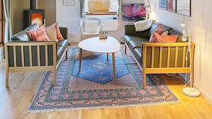 Ein gemütliches Wohnzimmer mit einer Sofagarnitur, einem Couchtisch, einem gemusterten Teppich und einer dekorativen Vase.