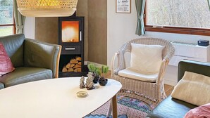 Ein gemütlicher Wohnraum mit Kamin, Korbmöbeln und Blick ins Freie.