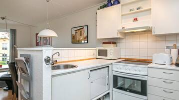 A compact kitchen with white appliances, a built-in oven, a microwave, and a sink.