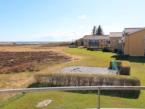 A residential area with a grassy field, a small pond, and a building with a balcony. - 4 Person Holiday Home in Hals (Hals)
