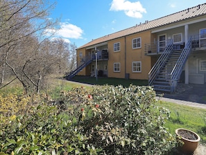 A building with a yellow facade, multiple windows, and a blue staircase leading to an upper level. - 4 Person Holiday Home in Hals (Hals)