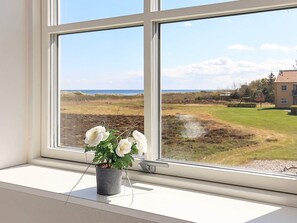 A window with a view of a grassy field, a building, and a body of water. - 4 Person Holiday Home in Hals (Hals)