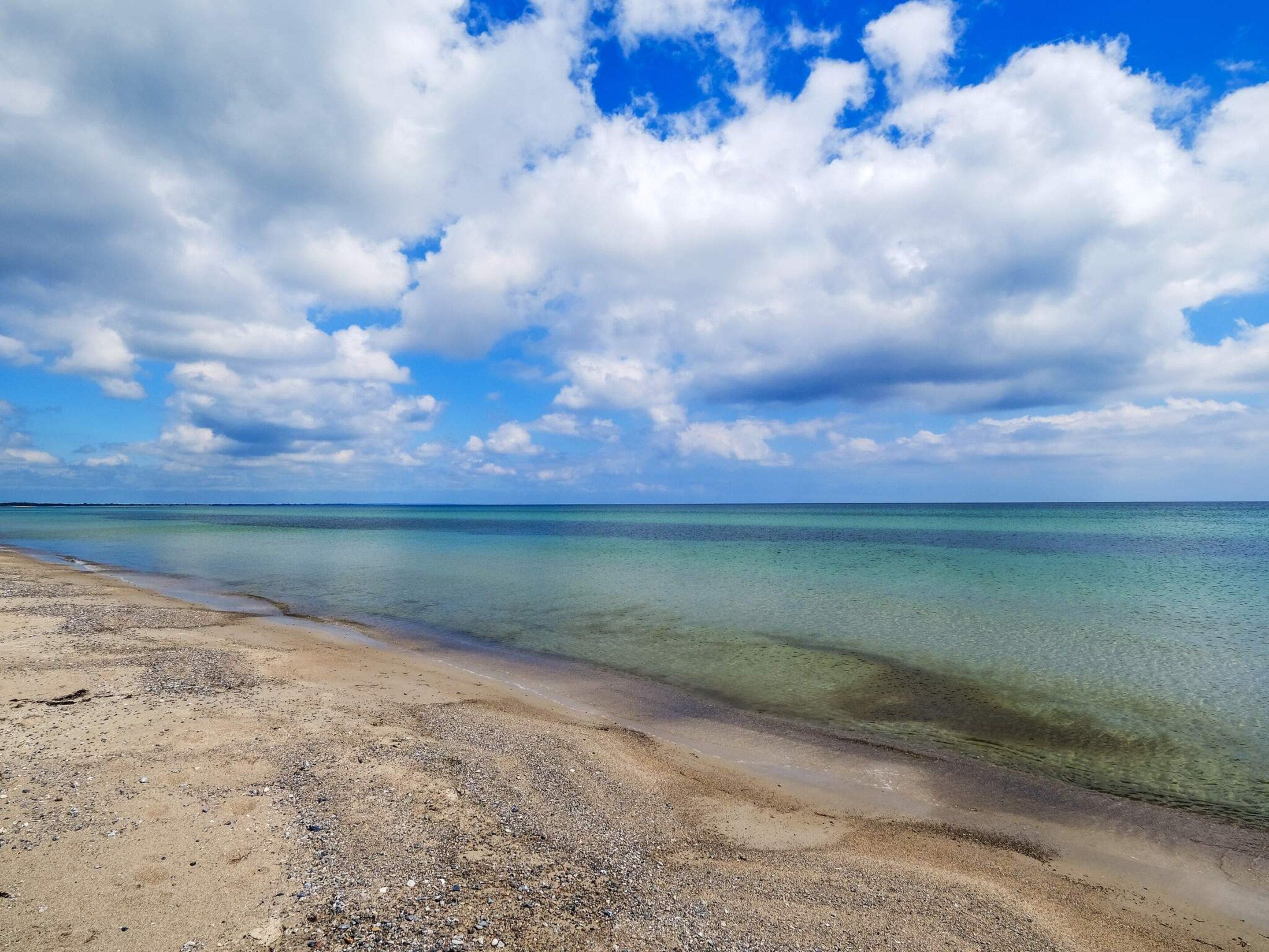 A beach with clear water and a sandy shore.