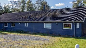 A single-story building with a dark blue exterior, a tiled roof, and a gravel driveway.