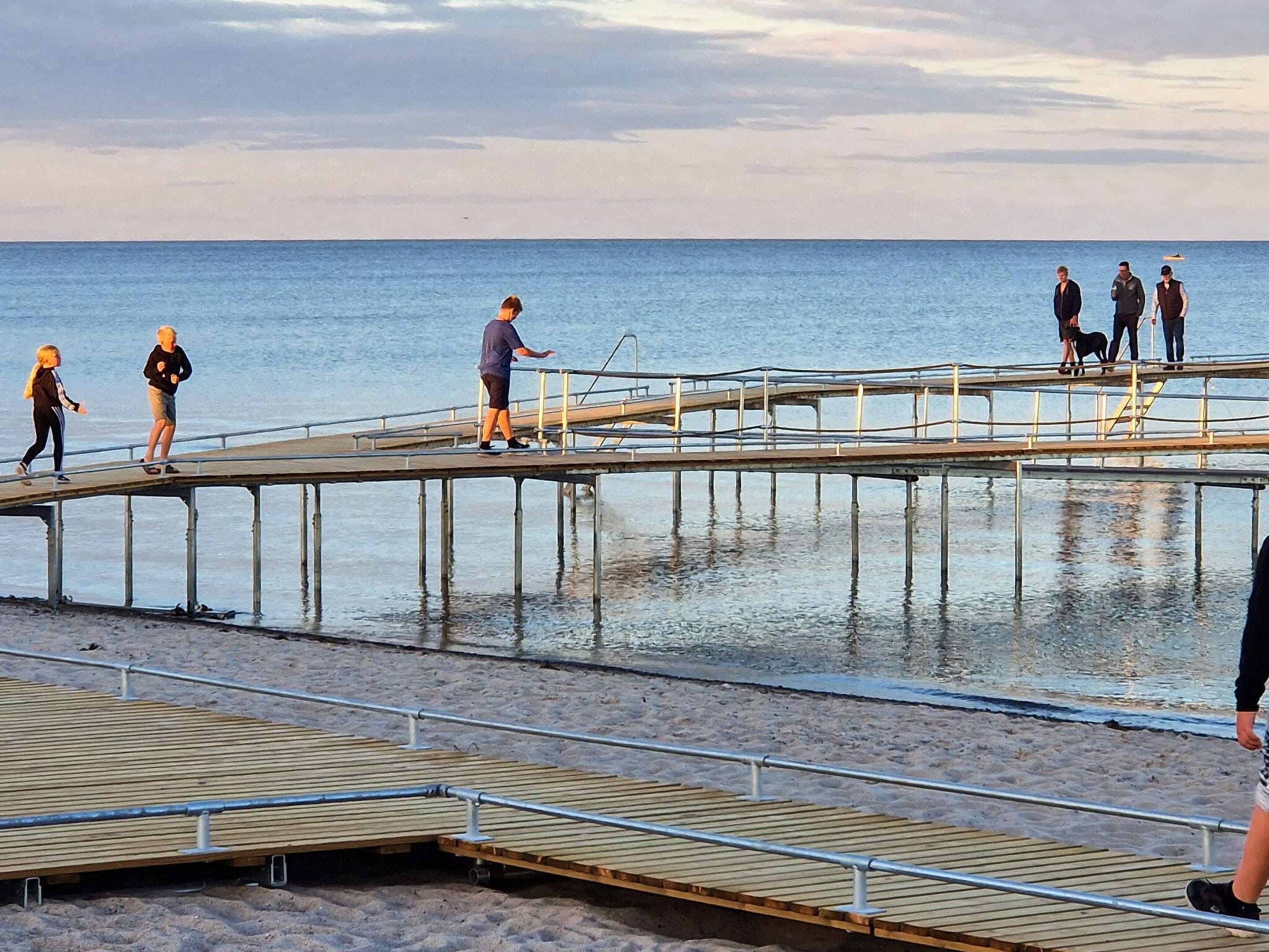 A pier extending into a body of water with people walking on it.