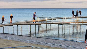 A pier extending into a body of water with people walking on it.