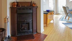 A room with a fireplace, wooden flooring, a dining area with a table and chairs, and a view of the outside.