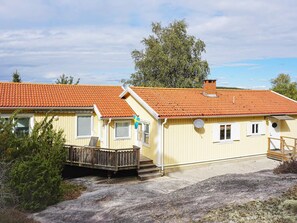A yellow building with a red-tiled roof, a wooden deck, and a flag. - 4 Star Holiday Home in Stromstad (Stromstad)