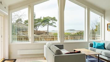 A living room with a large window, a grey sofa, a wooden coffee table, and a blue rug.