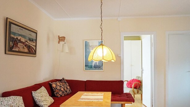 A living room with a red sofa, a wooden table, and a hanging lamp.