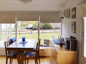 Un espace repas comprenant une table, des chaises et donnant sur l’extérieur.